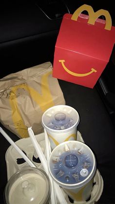 two plastic cups with lids and straws next to a mcdonald's bag