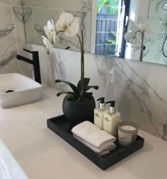 a bathroom counter with soap, lotion and flowers in the vase on it's tray