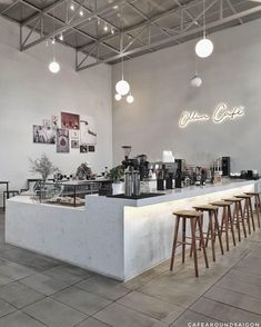 the interior of a coffee shop with several stools and lights hanging from the ceiling