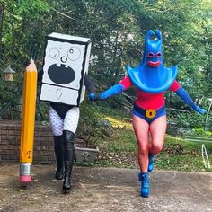 two people in costumes are walking down the street with crayons and pencils