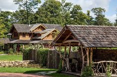 an old log cabin with stone walls and roof in the middle of a grassy area