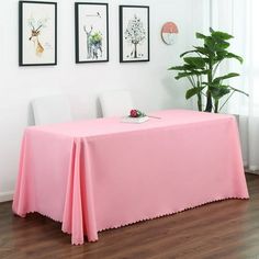 a pink table cloth with scalloped edges sits in front of three framed pictures