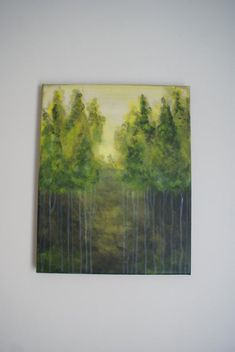 a painting hanging on the wall with trees in front of it and another painting behind it