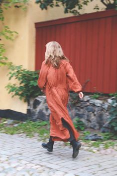 a woman in an orange dress is walking down the street