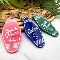 three key chains with the words beach house and cabana on them sitting next to a basket