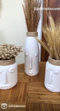 two white ceramic vases with dried plants in them