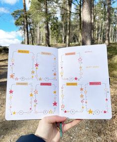 someone is holding up a planner in the middle of a forest with stars on it