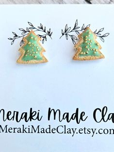 two small christmas trees are sitting on top of a sign that says merak made clay