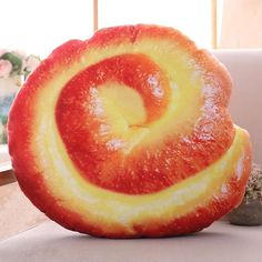 a large red and yellow doughnut sitting on top of a white table next to a potted plant