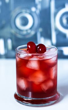 a red drink with two cherries in it