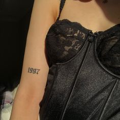 a woman with a small tattoo on her arm and chest is wearing a black dress