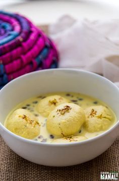 three balls of food in a white bowl on a table next to some cloths