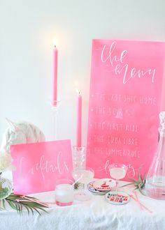 a table topped with pink signs and candles