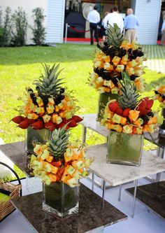 three vases filled with different types of fruit on top of a table in front of a house