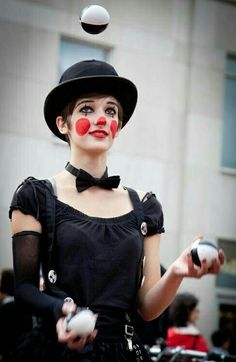 a woman dressed in clown makeup juggling balls