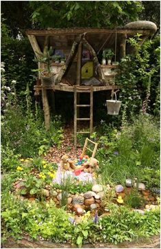 a garden with lots of plants and rocks in the ground, including a tree house