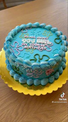 a birthday cake with blue frosting and writing on the top is sitting on a yellow plate