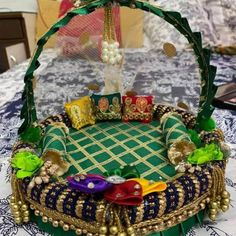 a green and gold decorated basket sitting on top of a white tablecloth covered table