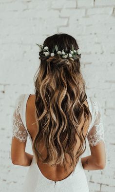 a woman with long curly hair wearing a white dress and flower headpiece in her hair