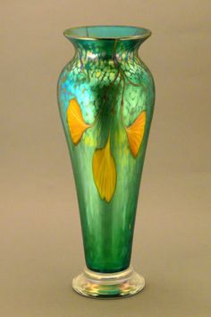 a green vase with yellow fish on it's body and water in the bottom