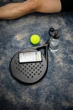 a tennis racquet and ball on the ground next to a bottle of water