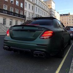 the rear end of a green mercedes c - class coupe parked on a city street