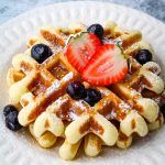 a waffle topped with fruit on top of a white plate