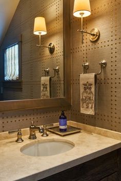 a bathroom sink under a large mirror next to a light fixture and two lights on the wall