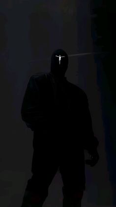 a person wearing a black jacket and mask in the dark