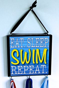 a sign that says eat sleep swim repeat hanging on a wall with three pairs of scissors