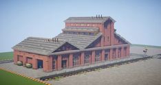 a large red brick building sitting on top of a lush green field next to a train track