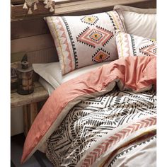 a bed with an orange and white comforter next to a wooden window sill