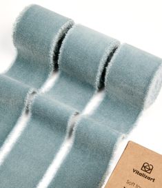 three rolls of blue cloth sitting on top of a white table next to a tag