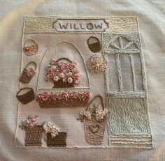 a white shirt with flowers and baskets on the front, along with an embroidered name sign that says willow