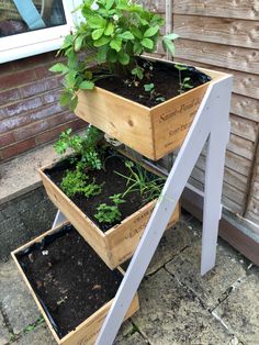 three planters are stacked on top of each other in front of a house, with plants growing out of them