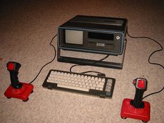 an old fashioned computer sitting on the floor next to two game controllers and a keyboard