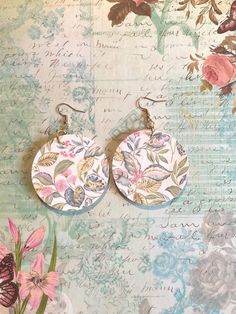 two pairs of floral print earrings on top of a piece of paper with flowers in the background