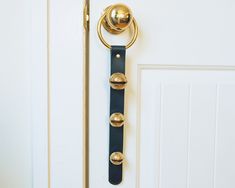 a door handle on a white door with gold knobs and a black leather strap