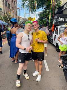 two men standing next to each other in the middle of a street with balloons and streamers