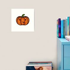 an orange pumpkin with a face drawn on it sitting next to a blue dresser and bookshelf