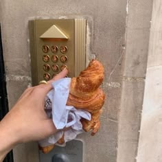 a person is holding a croissant in front of a hotel door lock with tissue paper on it