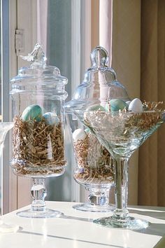 two glass vases filled with birds eggs on top of a table