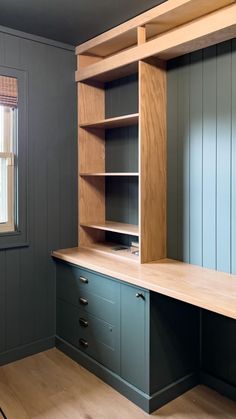 an empty room with wooden shelves and drawers