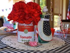 red carnations are in a can on a table with other items and decorations