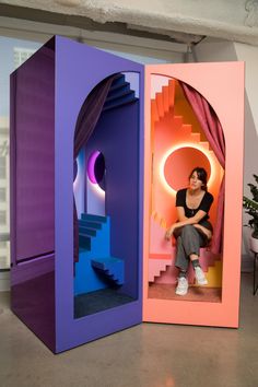 a woman sitting in a purple and pink room next to a stair case with stairs