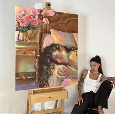 a woman sitting on a chair in front of a painting with flowers and a vase