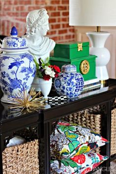 a table topped with blue and white vases next to a lamp