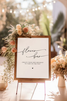 a sign that is sitting on top of a table with flowers and greenery in front of it