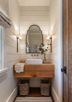 a bathroom sink sitting under a mirror on top of a wooden counter next to a door