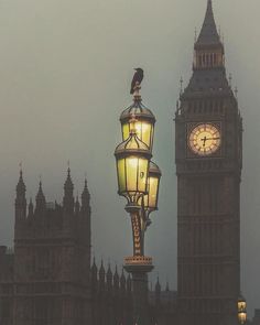 the big ben clock tower towering over london is lit up at night with yellow lights